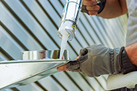 Duct service in Lacey technician applying sealant to exterior vent