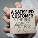 NJ NCR dealers help businesses run smooth "A satisfied customer is the best business strategy of all" written on a block being held out by a hand